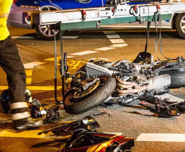 Motorcycle Accident Injuries after a serious road crash, showing a damaged motorcycle and emergency responders assisting an injured rider.