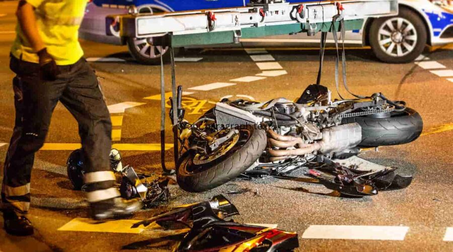 Motorcycle Accident Injuries after a serious road crash, showing a damaged motorcycle and emergency responders assisting an injured rider.