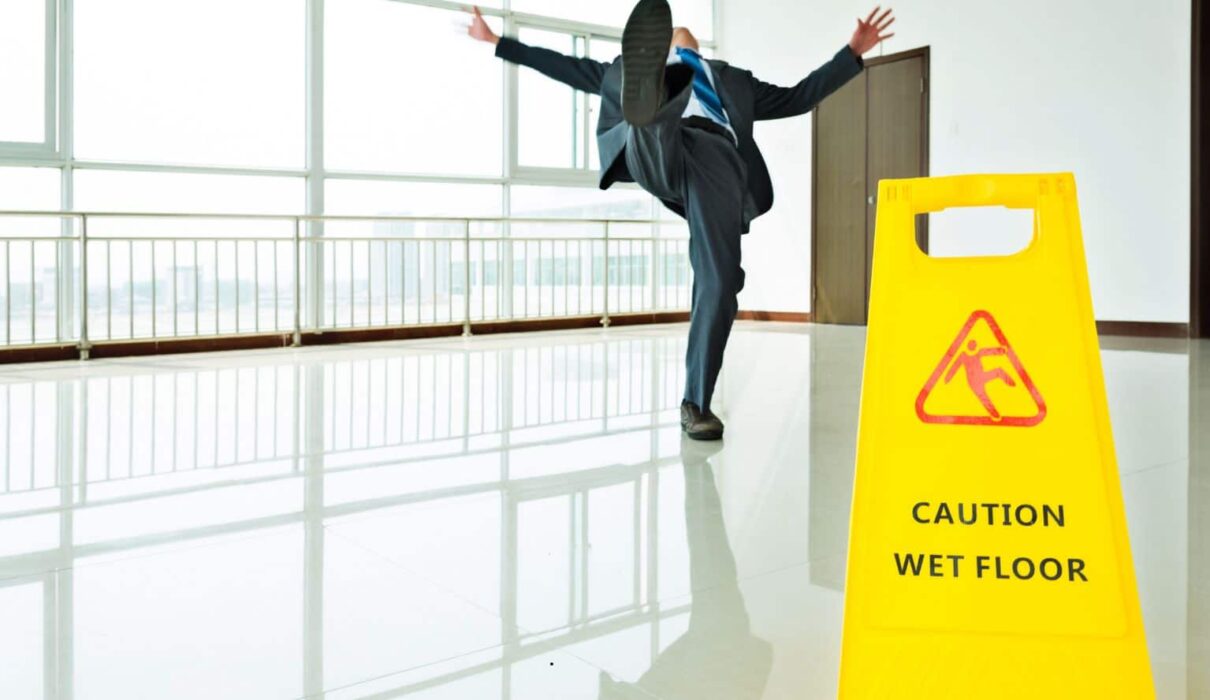 Person experiencing a Slip and Fall Accident on a wet floor in a public building, illustrating a common premises liability incident.