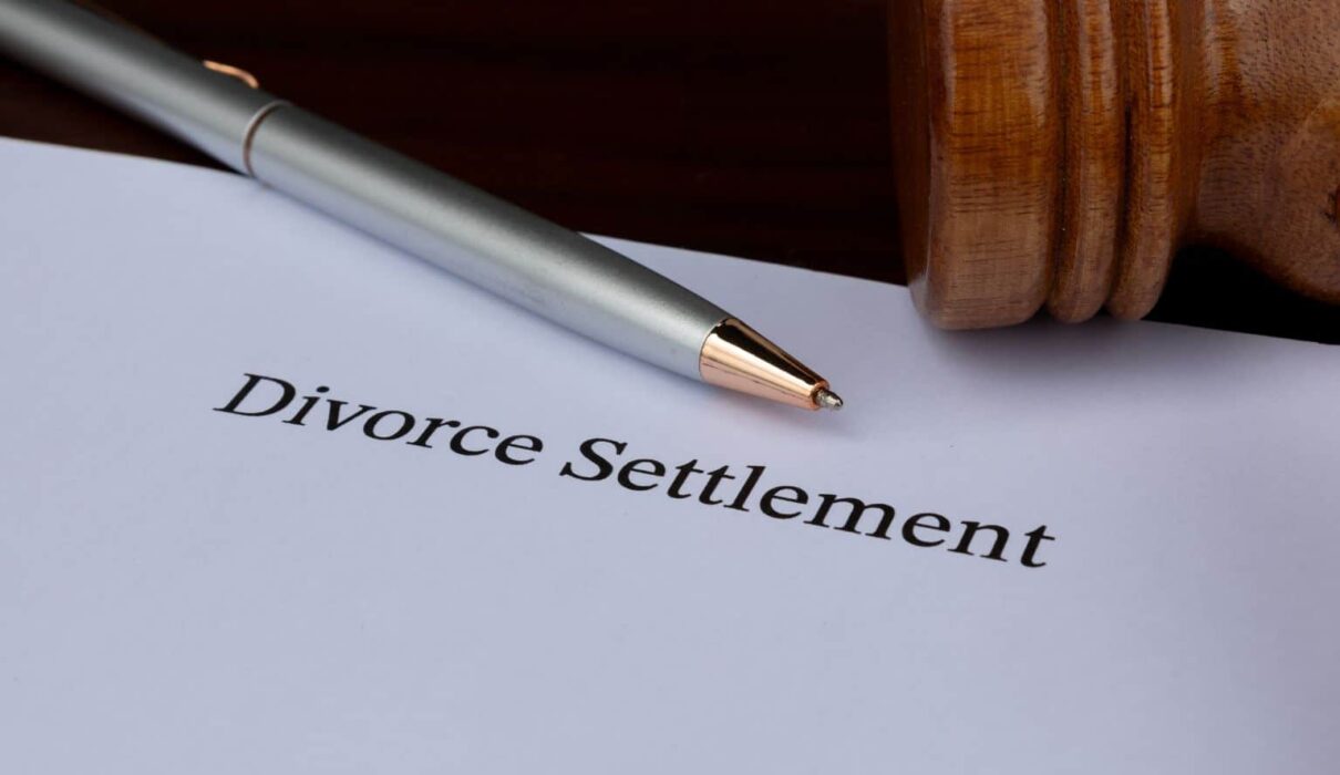Divorce Settlement Guide showing a couple reviewing legal documents with their attorneys during divorce settlement negotiations.