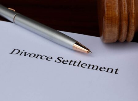 Divorce Settlement Guide showing a couple reviewing legal documents with their attorneys during divorce settlement negotiations.