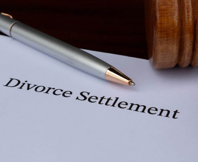 Divorce Settlement Guide showing a couple reviewing legal documents with their attorneys during divorce settlement negotiations.