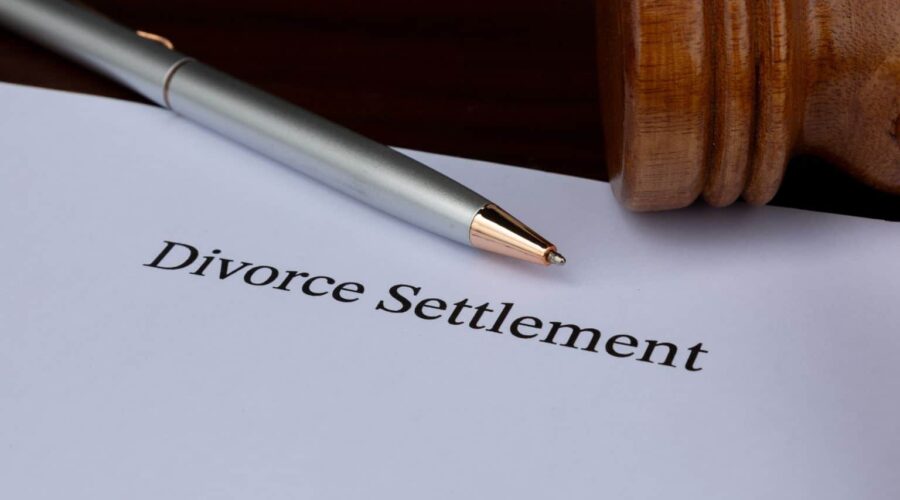 Divorce Settlement Guide showing a couple reviewing legal documents with their attorneys during divorce settlement negotiations.