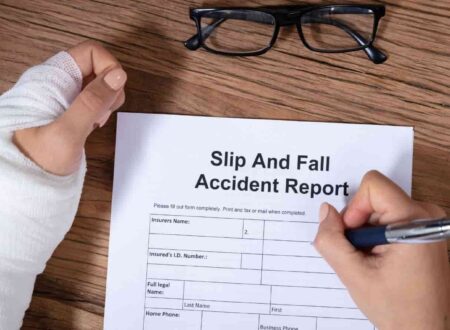 A person lying on the floor after a hazardous fall in a public building while a caution sign stands nearby, illustrating a Slip and Fall Lawsuit involving unsafe property conditions and injury claims.