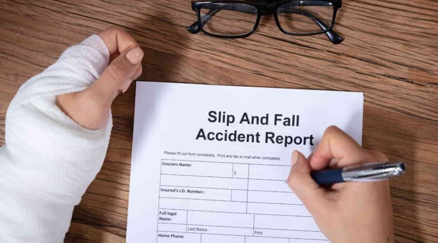 A person lying on the floor after a hazardous fall in a public building while a caution sign stands nearby, illustrating a Slip and Fall Lawsuit involving unsafe property conditions and injury claims.
