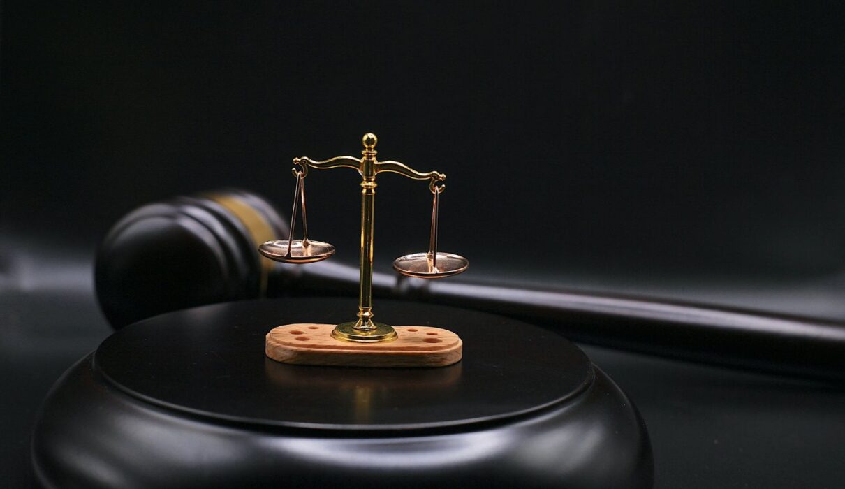 Gavel and scales of justice beside a blockchain network graphic, representing the OtterSec lawsuit over the crypto auditing firm's dissolution.