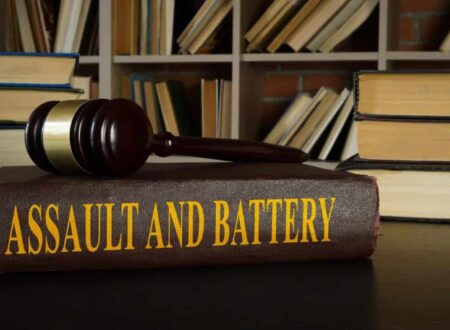 A courtroom-themed illustration representing Assault and Battery, showing a victim with visible injuries speaking to a lawyer while legal documents, a gavel, and scales of justice symbolize a civil and criminal legal case.