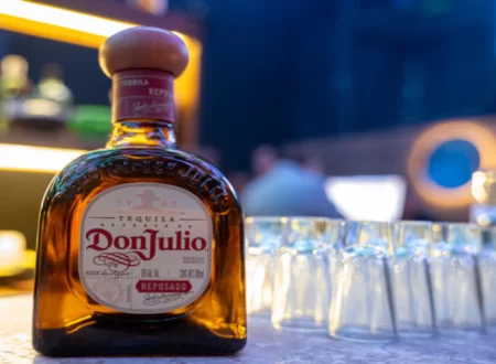 A bottle of premium tequila on a wooden counter with legal documents in the background.