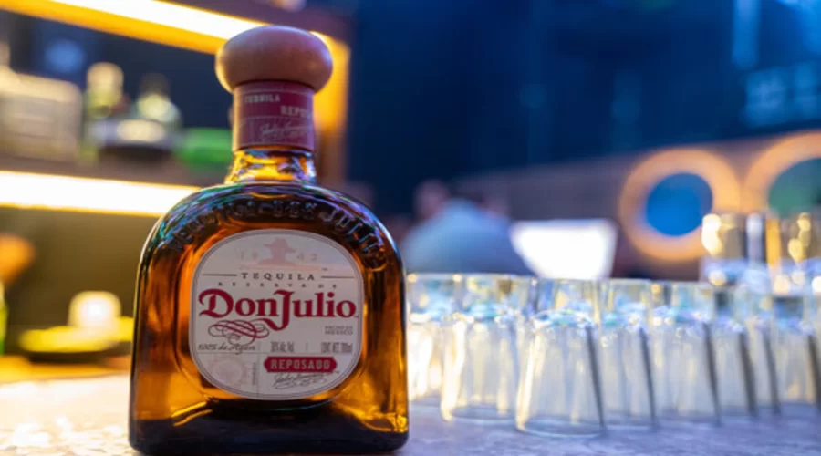 A bottle of premium tequila on a wooden counter with legal documents in the background.