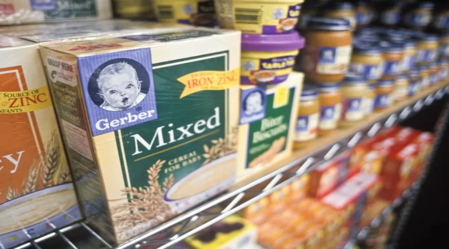 Illustration of a magnifying glass over a batch code on a baby snack box beside a recall alert icon