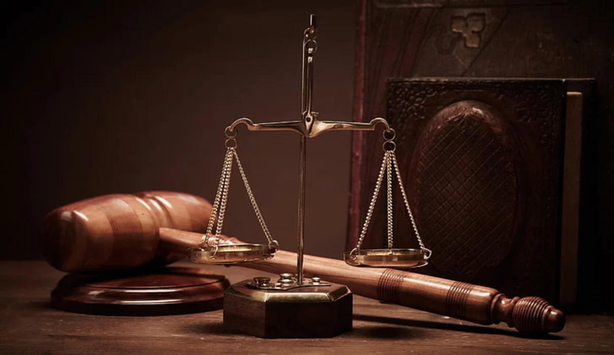 Illustration of scales of justice beside a Manhattan courthouse skyline for an article on Karen Friedman Agnifilo